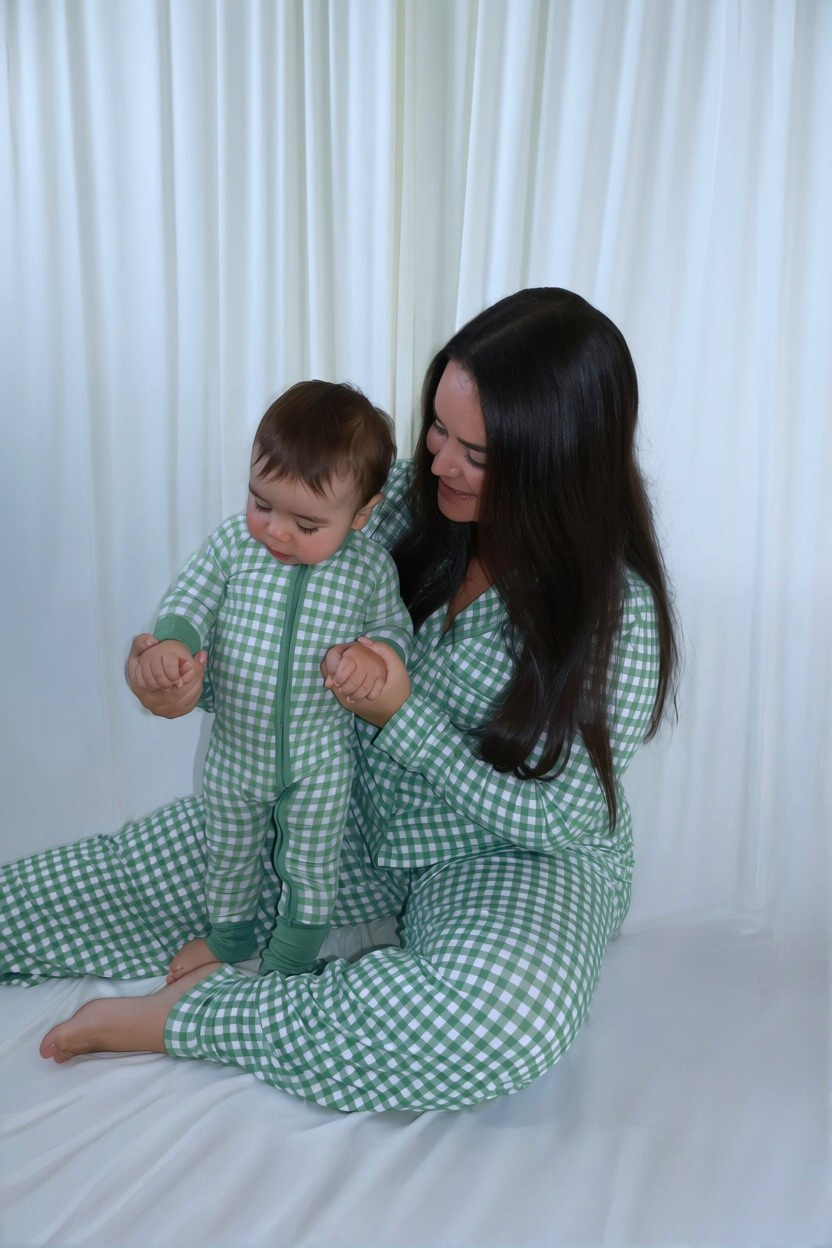 Mom holding her baby's hands, both wearing matching Goodnight Goose green gingham bamboo pajamas.