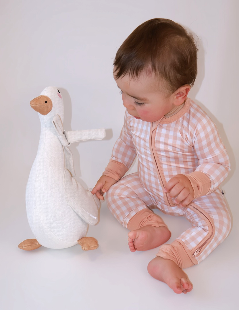 Baby wearing the Goodnight Goose peach gingham bamboo zippie with a two-way zipper and fold-over feet.