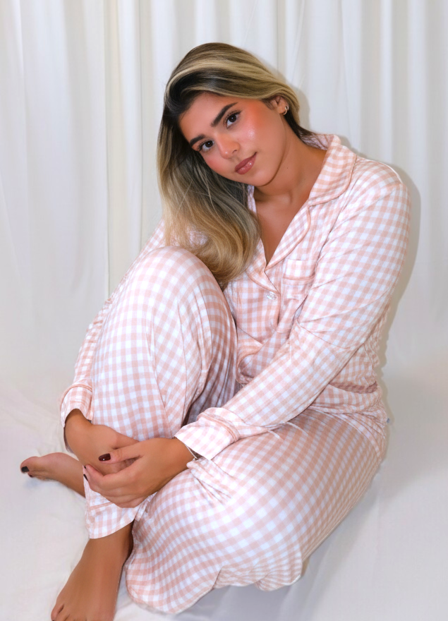 Woman wearing the Goodnight Goose peach gingham women's bamboo pajama set with a button-down top and matching pants.