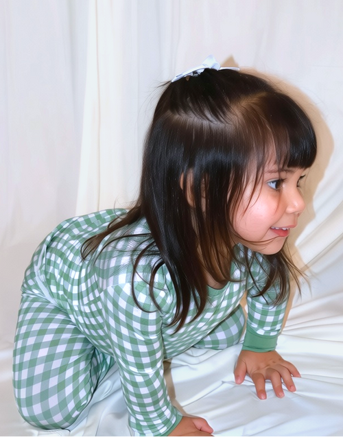 Child wearing the Goodnight Goose green gingham bamboo two-piece pajama set in a lifestyle photo.