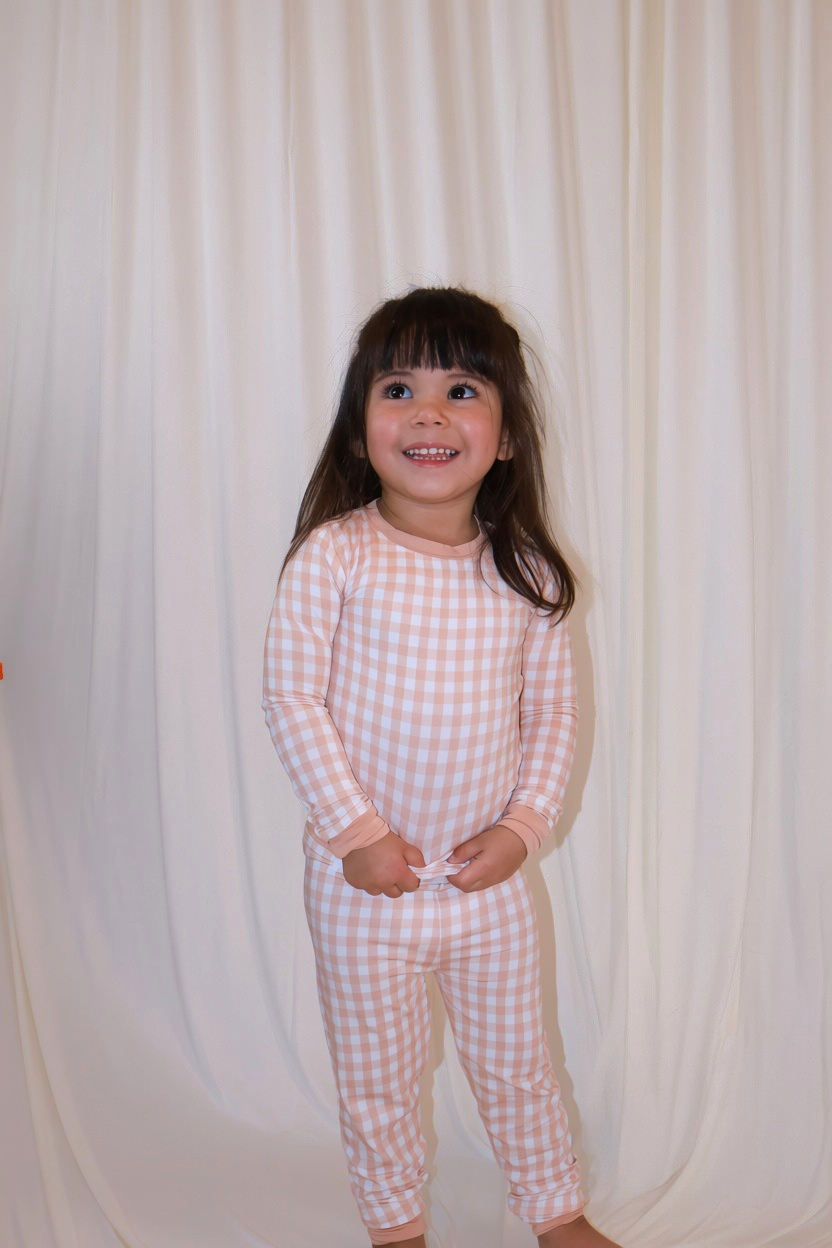 Toddler wearing Goodnight Goose peach gingham two-piece bamboo pajama set