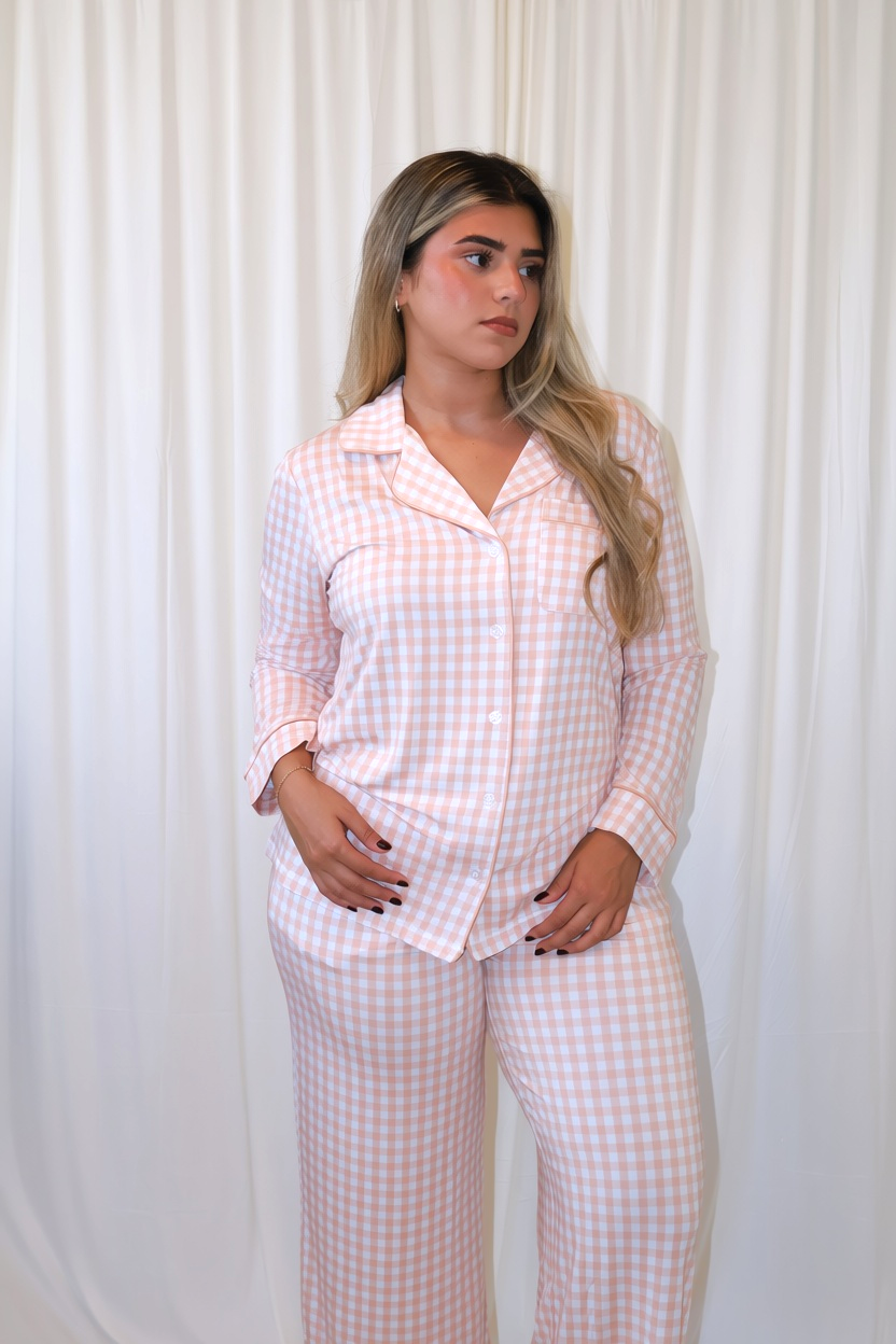 Woman wearing Goodnight Goose peach gingham women's bamboo pajama set with long-sleeve button-up top and matching pants